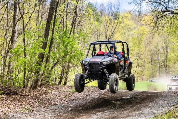 a rzr driving down a dirt road in a forest